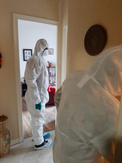Équipe Novalia Services — 3 techniciens en combinaison de protection intégrale et masques à gaz devant leur véhicule d'intervention, prêts à intervenir pour un nettoyage après décès