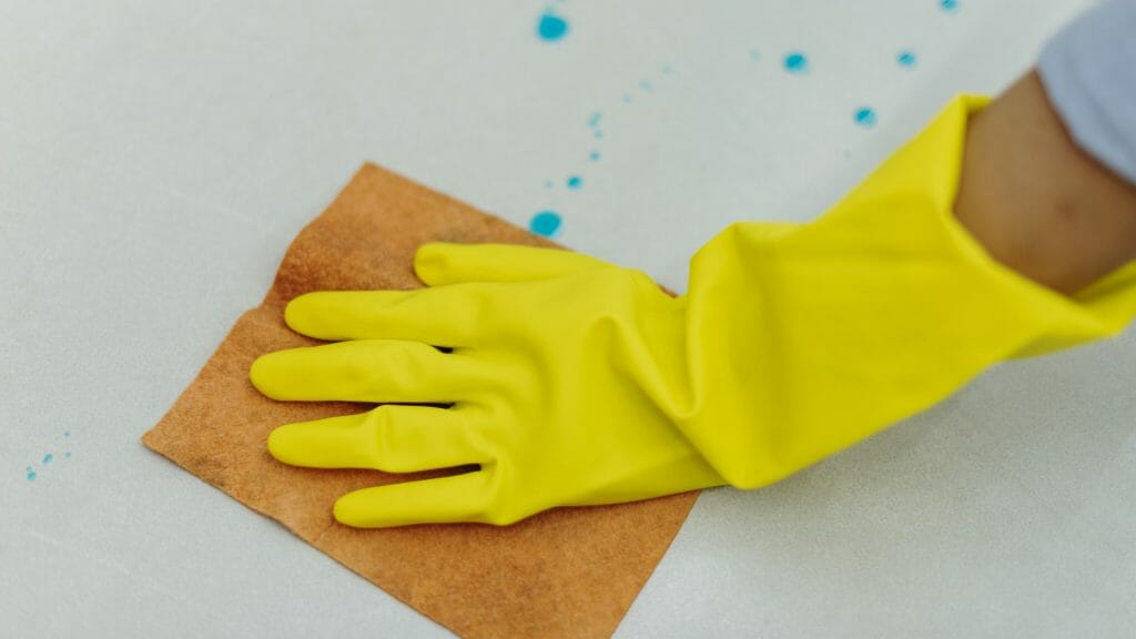 nettoyage d'une table avec un chiffon et des gants jaunes
